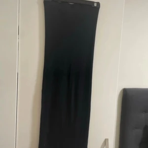 Svart långkjol från & Other Stories - Svart långkjol från & Other Stories i storlek S. Kjolen har en rak passform och en liten slits nedtill bak för extra rörelsefrihet. Enkel och stilren design som är lätt att matcha med olika toppar och skor.