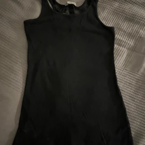 Svart ribbad linnetopp med spets - Snygg svart ribbad linnetopp från Lindex med spetsdetaljer och knappar i ryggen. Toppen är ärmlös och har en tight passform.