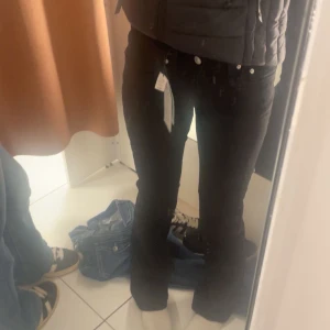 Svarta bootcut jeans låg midja - Hej! Jag säljer ett par helt svarta byxor, ett lågbindare med knappar bak. Jag har bara använt dem en gång, de är otvättade och helt rena. Byxorna var tyvärr för långa för mig, så jag säljer dem vidare. Nypris är 500 kr, men jag säljer dem för 450 kr eller 400 kr vid snabb affär. Fri frakt ingår och jag tar Swish eller kontakt som betalning. Hör av dig om du är intresserad! Säljer ett par svarta jeans med bootcut-modell och låg midja. Jeansen har klassisk femficksdesign, silverfärgade knappar oc