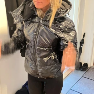 Shiny svart pufferjacka från Nelly - Säljer en glansig svart pufferjacka från Nelly med dragkedja och huva. 