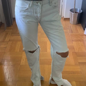 Ljusblå ripped jeans från Zara - Säljer ett par ljusblå jeans från Zara med raka ben, snygga slitningar vid knäna och slits på insida.