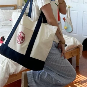 Trader Joe's väska - Stor och rymlig shoppingväska från Trader Joe’s med långa axelband och praktisk ytterficka. Köpt i Los Angeles, har en liten blå fläck på baksidan redan vid inköp. Perfekt för skola eller stan💙🤍