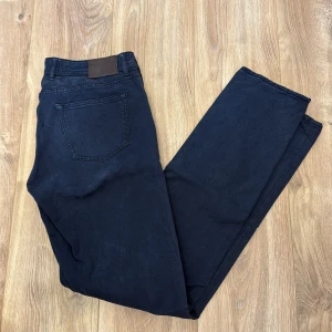 Mörkblå chinos från Oscar Jacobson - Snygga mörkblå chinos från Oscar Jacobson med klassisk passform och stilrena detaljer. Byxorna har en bakficka och är tillverkade i ett mjukt bomullsmaterial som känns bekvämt hela dagen. Perfekta för dig som gillar en clean och tidlös look.