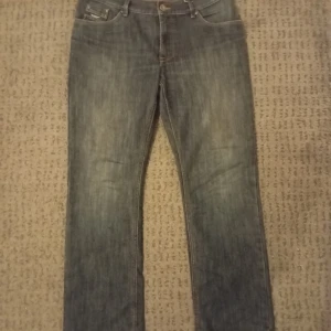 Mörkblå Hero jeans straight fit - Säljer ett par mörkblå jeans från Hero by John Heroox i storlek 34/34. Modellen har klassisk femficksdesign, raka ben och kontrastsömmar på bakfickorna. Jeansen är tillverkade i slitstarkt denim och har en snygg tvättad look.