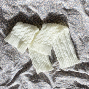 Vit stickade benvärmare med flätmönster - Supermysiga vita benvärmare med klassiskt flätmönster och breda ribbade kanter. Perfekt för kalla dagar när du vill hålla dig varm och ändå se stilren ut. 