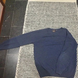 Mörkblå tröja från Oscar Jacobson - Säljer en stilren mörkblå tröja från Oscar Jacobson, tillverkad i Italien. Tröjan har en klassisk design med långa ärmar och rund halsringning. Skick: 9/10. Marinblå och perfekt inför våren.