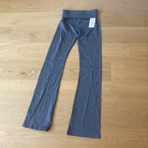 Grå bootcut leggings från Nelly XS - Snygga oanvända grå leggings från Nelly i storlek XS med bootcut-ben och låg midja. Mjukt och stretchigt material som sitter skönt och följer kroppen. Perfekta för en trendig och avslappnad look.