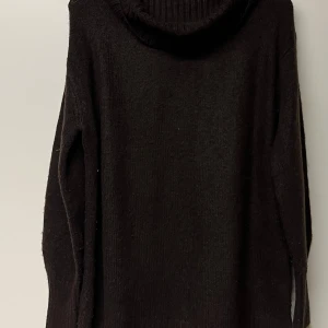 Mörkbrun polotröja stickad  - Mysig mörkbrun polotröja med bred, ribbad krage. Stickad i mjuk ull och har långa ärmar med ribbade muddar. Perfekt för kyliga dagar och enkel att matcha med jeans eller kjol. Snygg och enkel design som ger en chill vibe.