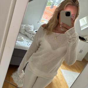 Vit stickad offshoulder-tröja - Säljer en superfin vit stickad tröja med offshoulder-modell. Tröjan är tunn och har lång ärm, perfekt för lager-på-lager eller till ett par snygga jeans. Enkel och stilren design som passar till många olika outfits.