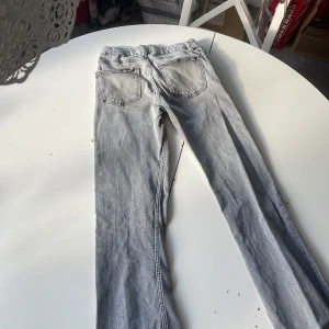 Grå jeans från Gina Tricot, storlek 152 - Snygga grå jeans från Gina Tricot i storlek 152. Klassisk femficksmodell med raka ben och normal passform. Jeansen har silverfärgade knappar och bälteshällor, perfekta till en avslappnad stil.
