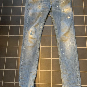 Dondup george jeans - Ljusblå slim fit jeans från George med slitna detaljer och hål på benen. Jeansen har klassisk femficksdesign, röda sömmar vid linningen och är tillverkade i denim. Perfekta för dig som gillar en avslappnad och trendig look.