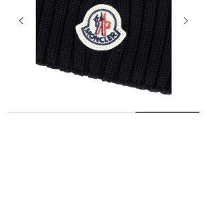 Svart ribbstickad mössa från Moncler - Svart ribbstickad mössa från Moncler med klassisk uppvikt kant och broderad logotyp framtill. Tillverkad i mjukt material som håller dig varm och ger en clean look. Perfekt accessoar för kyliga dagar och snygg till streetwear.