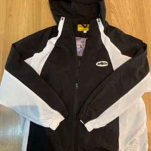 Corteiz windbreaker - Säljer en svart och vit vindjacka från Corteiz med huva och dragkedja framtill. Köpt,  men jag säljer eftersom att  passformen var inget som passade just mig. Perfekt till hösten! (Nypris 1700kr)