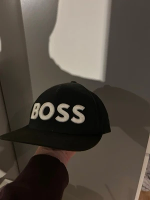  Hugo Boss keps med broderad logga - Säljer en svart boss keps från BOSS, Justerbar baktill för perfekt passform. Lite smutsig men går att rengöra