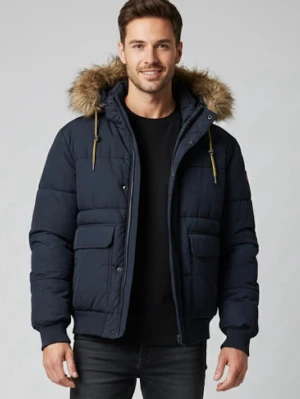 Mörkblå pufferjacka med fuskpäls från H&M - Säljer en mörkblå pufferjacka från H&M med huva och fuskpäls. Jackan har stora fickor framtill, dragkedja och gula snören vid huvan. Perfekt för kalla dagar och riktigt snygg till jeans eller hoodie.