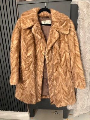 Äkta minkkappa - Äkta minkpäls bred krage och snyggt mönstrad päls. Jackan har ett klassiskt snitt och är helfodrad med brunt tyg på insidan. Perfekt för dig som vill sticka ut och hålla dig varm under kalla dagar.  Står ingen storlek på den men skulle säga S!