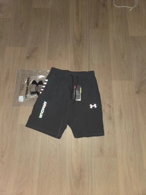 Gråa träningsshorts Under Armour - Gråa Underarmour Medium shorts som funkar till gymmet,aktiviteter,löpning,etc.. De är helt nya och oanvända de har den original påsen som ni ser på bilden.