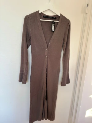 Trendig lång brun kofta  - Ribbad lång klänning/kofta i brun färg med knappar hela vägen 🤎 Kan bäras både stängd som klänning eller öppen som kofta. Vida armar och superfin passform – väldigt trendig modell.  Aldrig använd, prislappen kvar. ▫️ Märke: Lager 157 ▫️ Storlek: S ▫️ Skick: NY  Hör av dig vid frågor eller intresse ✨