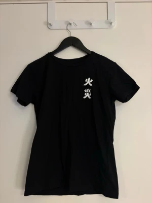 Dam Svart t-shirt med japanskt tryck - Säljer en svart t-shirt med egen gjord vita japanska tecken tryckta på bröstet och ryggen. T-shirten har klassisk passform och rund hals. Materialet känns mjukt och skönt, perfekt till vardags. Enkel men ändå unik design som sticker ut.