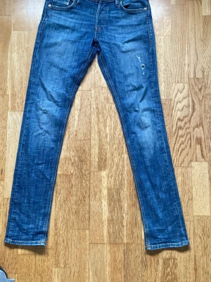 Blå smala jeans med slitningar - Säljer ett par blå jeans från Jack and Jones med smal passform och snygga slitningar på benen. Jeansen har normal midja och är tillverkade i slitstarkt denimtyg, det är storlek 29 34 men sitter som 29 32. Hör av dig om du har några frågor, mvh //Emil