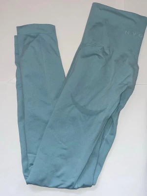 Blå träningstights från NVGTN - Snygga blå träningstights från NVGTN med hög midja och tight passform. Tillverkade i ett stretchigt syntetmaterial som sitter skönt och följsamt. Perfekta för träning eller när du vill ha en sportig look.