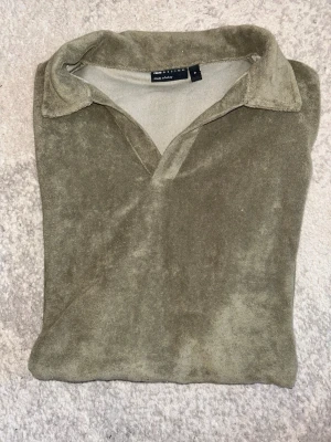 Grön (khaki) frottépiké från ASOS. - Säljer en grön pikétröja i mjuk frotté från ASOS. Tröjan har korta ärmar, klassisk krage och avslappnad passform. Perfekt för sommardagar eller en chill look. Hör av er vid intresse/ frågor!