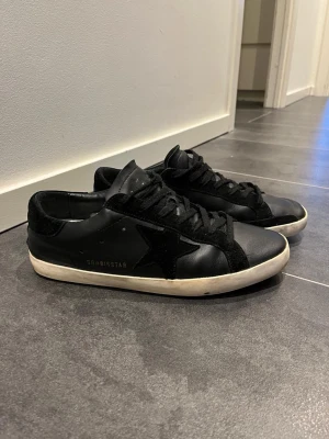 Golden Goose Superstar Skor svart - Säljer dessa tvärfeta o ganska sällsynta golden goose skor i svart färg med vita sulor. De passar perfekt nu inför våren, och även andra årstider. Skorna är storlek 45, använda men i bra skick. Förutom att hälen skrapats lite, dock syns det inte när man använder de. Nypris: 5000-6000kr.