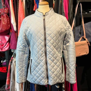 Ljusblå quiltad jacka från Freequent - Snygg ljusblå quiltad jacka från Freequent med raka linjer och hög krage. Jackan har dragkedja framtill, två fickor med dragkedja och ett rutigt quiltat mönster över hela ytan. Perfekt för dig som gillar stilren och modern look.