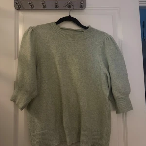 Ljusgrön stickad tröja med puffärm - Superfin ljusgrön stickad tröja med puffiga trekvartsärmar och bred ribbad mudd vid ärmslut och nederkant. Tröjan har en rund halsringning och är perfekt för dig som gillar en mjuk och mysig stil med lite extra volym på ärmarna.