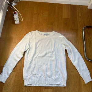 Vit stickad tröja från VILA - En enkel och stilren vit stickad tröja från VILA i storlek L. Tröjan har rund hals, ribbade muddar vid ärmslut och nederkant samt långärmad passform. Perfekt för lager-på-lager och chill dagar. Materialet är mjukt och bekvämt. En liten skavank på bröstet men inget man tänker på💓