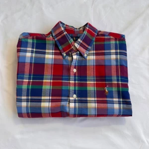 Rutig skjorta från Ralph Lauren M - Färgglad rutig skjorta från Ralph Lauren i slim fit stretch oxford. Skjortan har klassisk krage, knappar framtill och broderad logga på bröstet. Färgerna är röd, blå, grön, gul och vit. Perfekt för dig som gillar en preppy och stilren look. Nypris: 1700kr✅💯