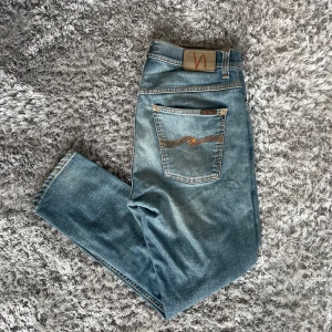 Nudie Jeans Tape Ted Brilliant Blues - Säljer nu dessa Nudie Jeans i den populära passformen Tape Ted | Använt men fortfarande i bra skick | Lagade på båda bakre fickorna samt i skrevet, samt en litet skrap på ena knäet (SE BILDER) | Strl: W30 L28 | Färg: Brilliant Blues | Nypris: ~1400kr | Hör av dig vid minsta fundering :) 