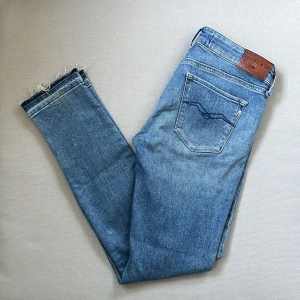 Replay skinny jeans ljusblå med orginalslitningar, stl 27 - Säljer ett par ljusblå skinny jeans från Replay, modell LUZ. Jeansen har klassisk femficksdesign, slitna detaljer och råa benslut. Snyggt Replay-läderpatch bak och diskret logga på fickan. Perfekta för dig som gillar en tight passform och trendig look.