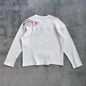 Derschutze Blossom Vit långärmad tröja med broderi - Vit långärmad tröja från Derschutze ett snyggt rosa broderi av blommor på axeln baksida . Tröjan har en rak passform och är tillverkad i ett mjukt, ribbat material som känns skönt mot huden. Den har fortfarande tagg kvar. Storleken är XL men skulle säga att den passar på L också.