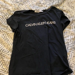 Svart t-shirt från Calvin Klein Jeans - Snygg svart t-shirt från Calvin Klein Jeans med vit logga på bröstet. Perfekt för en casual look. Tillverkad i mjukt material för extra komfort. 