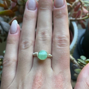 Silvrig ring med grön sten - Unik handgjord ring i silverfärgad metall med en rund, ljusgrön sten i mitten. Ringen är i storlek M (18 mm i diameter). Om annan storlek önskas så kan jag ordna det också😁Fler ringar finns på min profil!