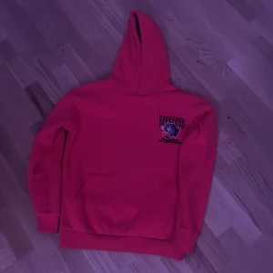 Röd hoodie Reckless med pantermotiv - Röd hoodie från Reckless med stor pantermotiv och text på ryggen samt mindre tryck på bröstet. Klassisk känguruficka framtill och huva. Perfekt för dig som gillar streetstyle och vill sticka ut med en cool design.(oversized)