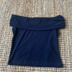 Mörkblå offshoulder topp Gina Tricot - Snygg mörkblå offshoulder topp från Gina Tricot. Toppen är axelbandslös med en sorts foldover över axlarna ( ungefär som ett par yoga pants ) och passar till nästan allt! endast använd ett par gången och har inga defekter ❣️