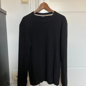 Svart stickad tröja Jack & Jones L - En svart stickad tröja från Jack & Jones Premium i storlek L. Tröjan har rund halsringning och långärmad passform. Enkel och stilren design som funkar till många olika outfits. Perfekt för kyligare dagar.