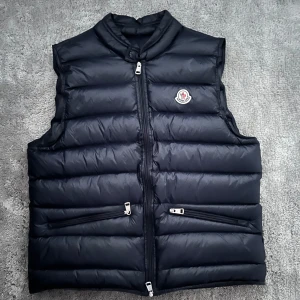 Moncler Gui väst Navy Blue  - En moncler väst i mycket bra skick som ny. Storleken är 2 så s/m. 29797212UOVL säljs från brandofnordic HB. Skicka för mer info och bilder 