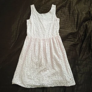 Ljusrosa spetsklänning Hampton Republic - Superfin ljusrosa ärmlös klänning från Hampton Republic med blommig spets över hela klänningen. Den har rundad halsringning, markerad midja och knappar i ryggen. Perfekt för fest eller sommarens alla tillfällen. Söt och klassisk modell som känns både fräsch och stilren.