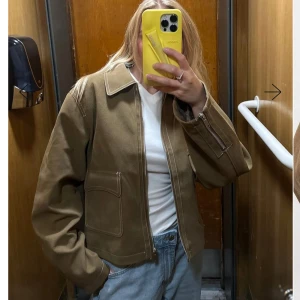 Nakd Jacka - Snygg brun jacka från NAKD markerade vita sömmar, stora fickor framtill och dragkedja både fram och vid ärmslut. Jackan har en loose passform. Nypris 1199kr prislapp finns kvar ej använd.