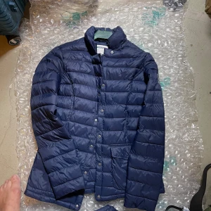 Mörkblå pufferjacka från Race Marine - Säljer en mörkblå pufferjacka från Race Marine med snyggt quiltad design och hög krage. Jackan har tryckknappar framtill, två stora fickor och en patch med logga på ärmen. Perfekt för kyliga dagar och enkel att styla till det mesta.