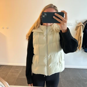 Beige/vit dunväst - Snygg beige/vit dunväst med stor huva, perfekt till hösten.
