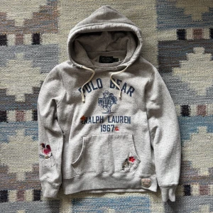 Grå hoodie Polo Bear Ralph Lauren - Grå ralph Lauren hoodie med ikoniskt Polo Bear-tryck + broderade detaljer. huva, känguruficka & tryck fram/bak. Skön passform, perfekt för chill dagar.  🧾 Nypris: 3300 kr ✅ Fint skick 