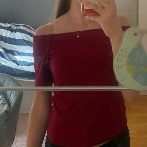 Röd Off shoulder topp från H&M - Säljer en jättefin vinröd off shoulder tröja från H&M med korta ärmar. Tröjan är nästan aldrig använd och modellen sitter snyggt. Priset kan diskuteras!