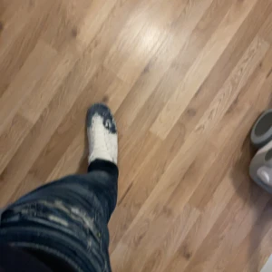 Mason margiela sneakers blå/vit - Säljer ett par unika Mason margiela sneakers i vitt med blå färgstänk och coolt mönster på tån och sidorna. Skorna har snörning och platt sula, perfekt för dig som vill sticka ut med en exklusiv streetstyle-look.