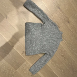 Grå polotröja från & Other Stories - Mysig grå polotröja från & Other Stories med hög hals och lång ärm. Tröjan är stickad i ett fluffigt material som känns både mjukt och varmt, perfekt för kyliga dagar. Enkel och stilren design som funkar till allt. Det är en skön och mysig ull tröja. Helt oanvänd.😁💕