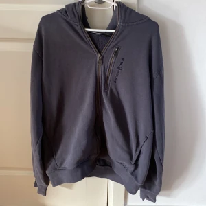 Mörkblå hoodie från Sail Racing - Snygg mörkblå hoodie från Sail Racing i storlek L. Tröjan har huva, hel dragkedja och en extra zipficka på bröstet.