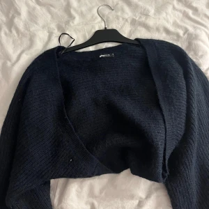 Mörkblå stickad kofta  - Mysig mörkblå stickad kofta från Gina Tricot i storlek XS. Koftan har en öppen front och är tillverkad i ett fluffigt, stickat material som passar perfekt för kyliga dagar. Enkel och stilren design som är lätt att matcha med olika outfits. Aldrig använd och helt ny 💕💕
